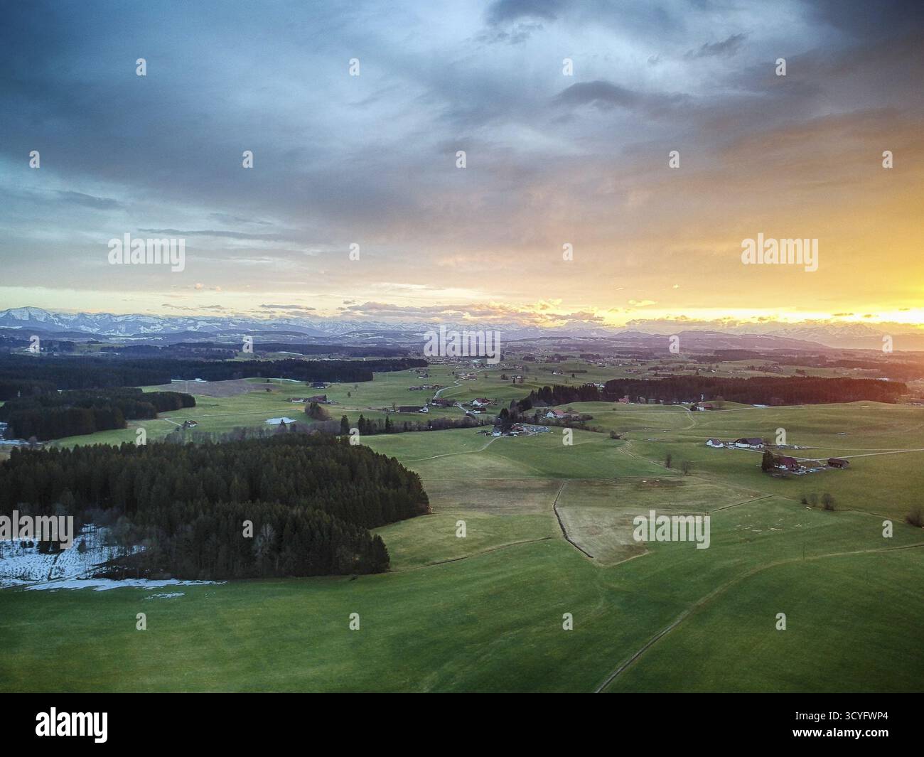 Splendido e tranquillo paesaggio con un cielo arancione e rosa brillante. Il cielo è pieno di nuvole e il sole sta tramontando, proiettando un caldo bagliore sulla lan Foto Stock