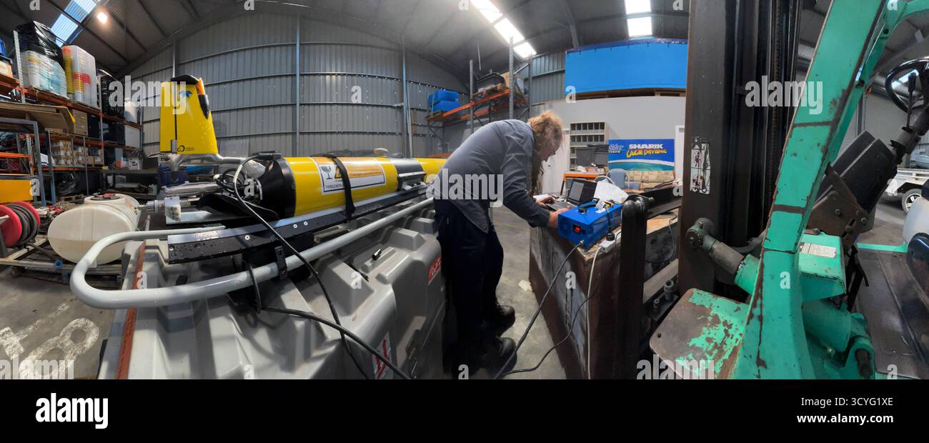 Tecnico di alianti Slocum che lavora sui dati e ricarica all'interno di un grande capannone industriale, Port Lincoln, Australia meridionale. No MR o PR Foto Stock