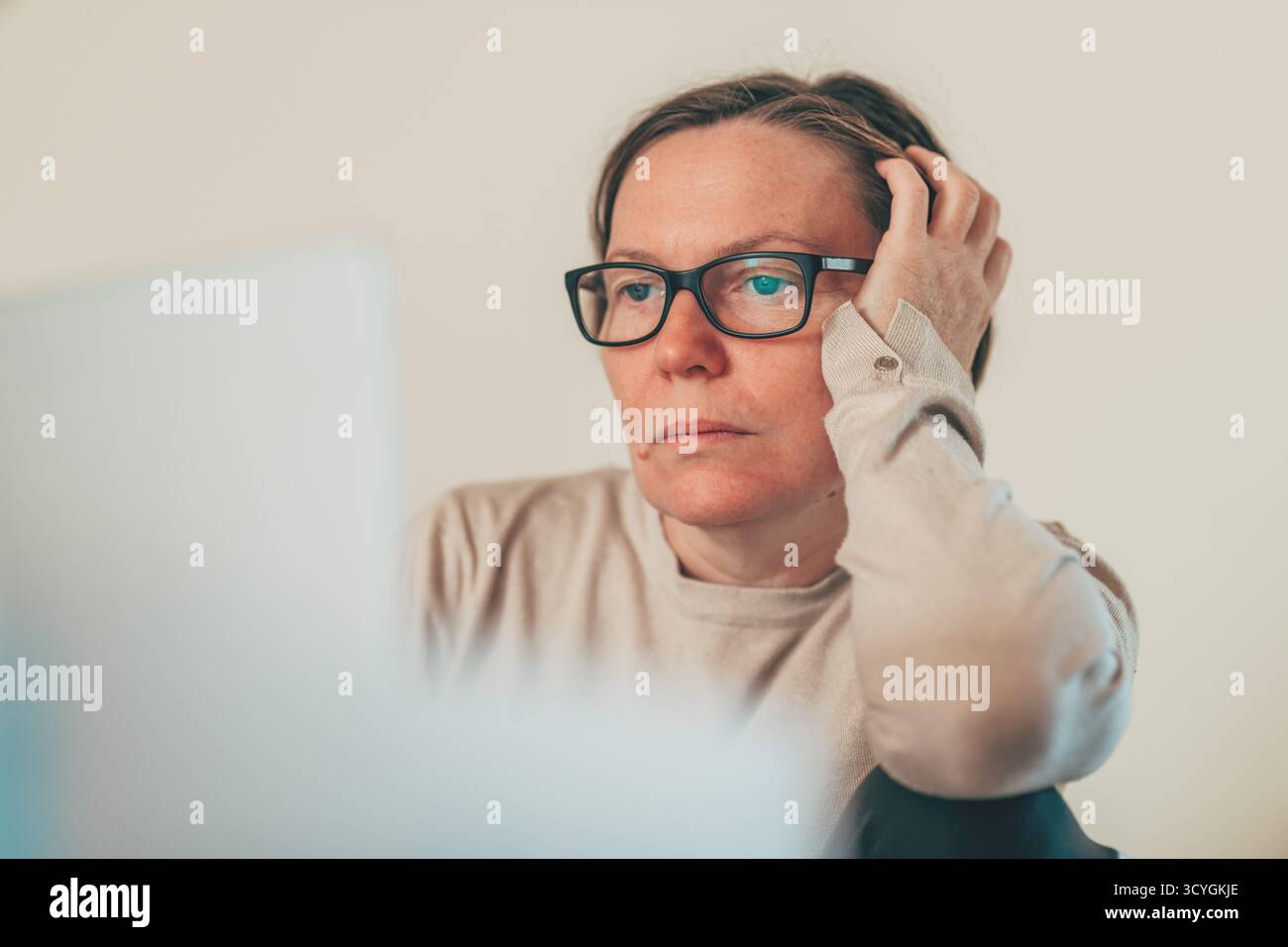 Donna adulta matura in un abbigliamento casual, stressata e frustrata mentre lavora al computer portatile a casa. Messa a fuoco selettiva. Foto Stock