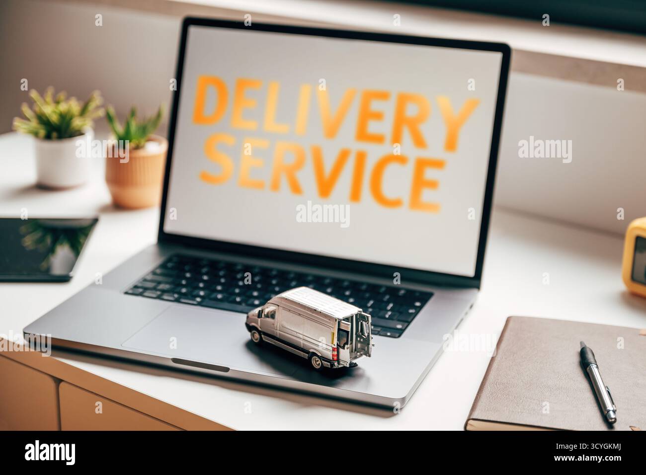 "Computer portatile con testo "Delivery Service" e modello di furgone in miniatura su tastiera, che simboleggia la logistica, la spedizione e l'e-commerce delivery conc. Foto Stock