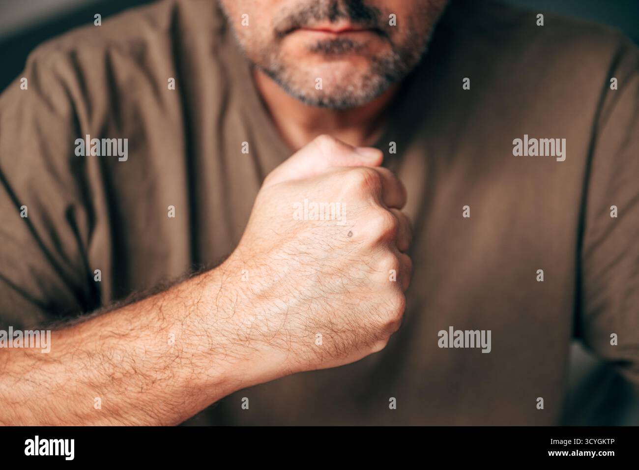 Uomo determinato che stringe il pugno in primo piano, simboleggiando forza e resilienza. Mano maschile con pugno stringato in primo piano stretto, concetto di potere, de Foto Stock