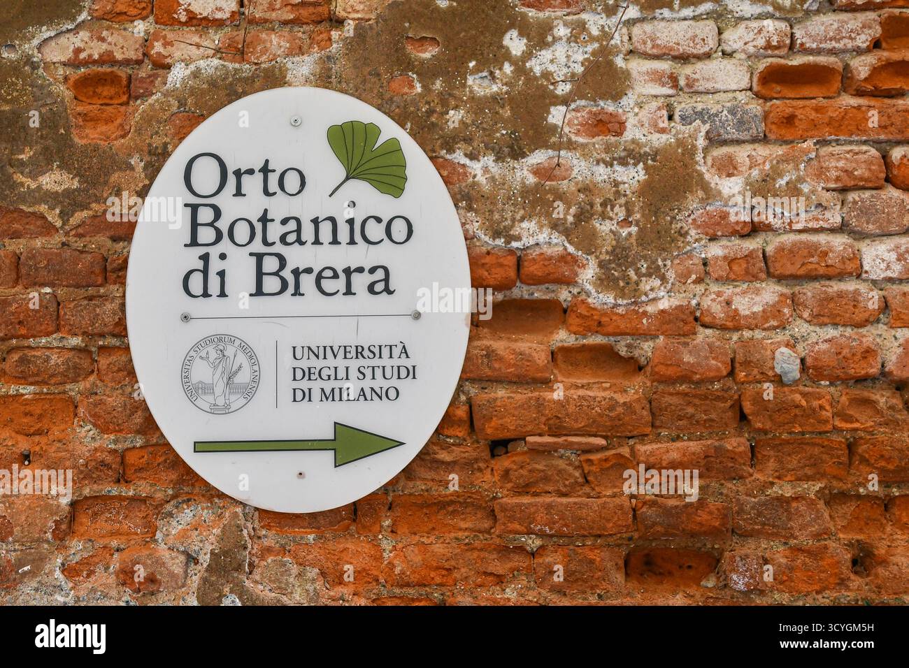 Primo piano di un cartello di direzione dell'Orto Botanico di Brera, giardino storico gestito dall'Università degli studi di Milano su un'antica parete di mattoni, Milano, Lombardia, Foto Stock