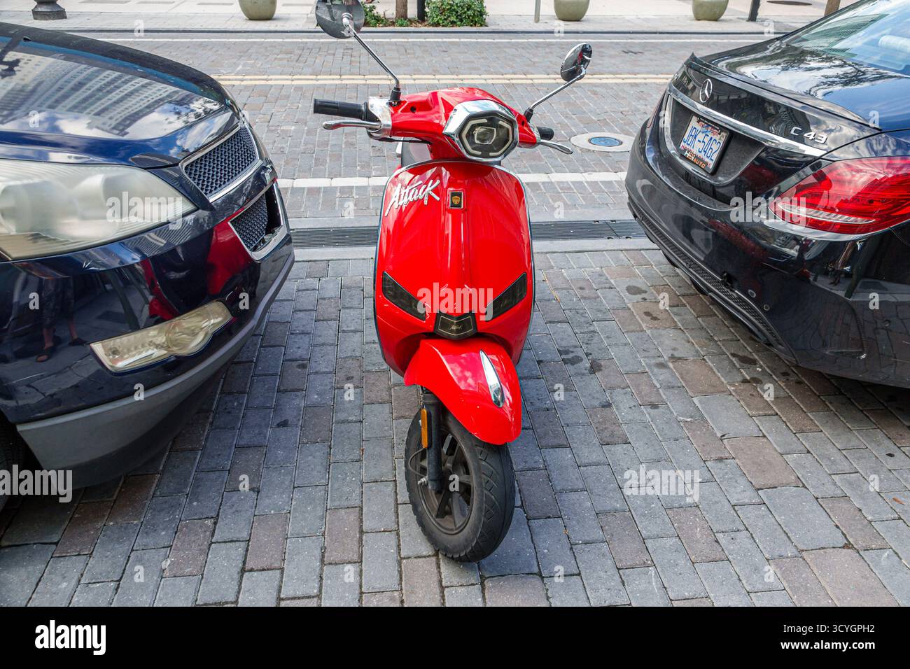 Miami, Florida, centro di Flagler Street, scooter Red Attack parcheggiato tra due auto, trasporto moto, veicolo compatto, mobilità urbana Foto Stock