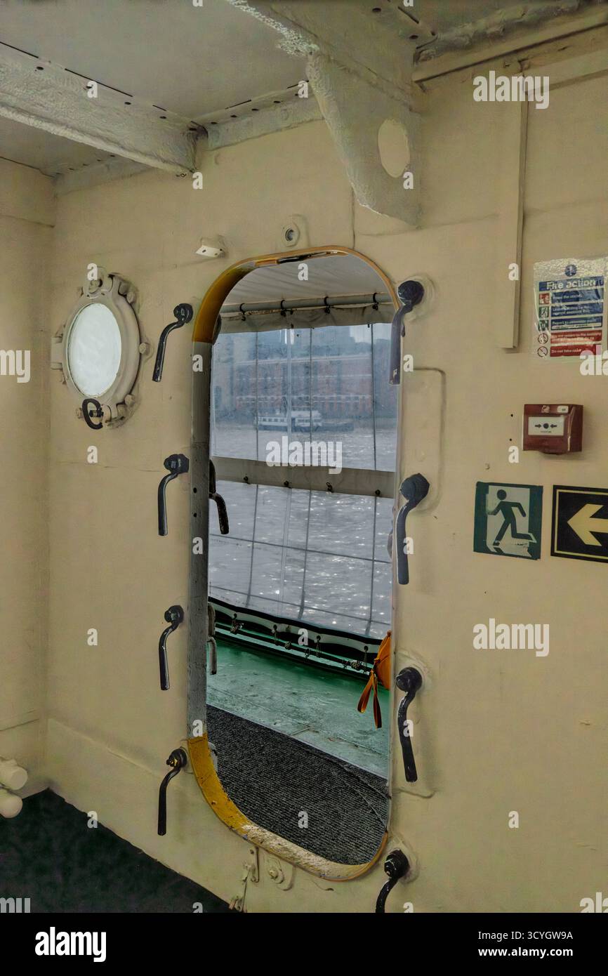 Porta e oblò interni a tenuta stagna a bordo della HMS Wellington sul Tamigi, Londra, che mostra i dettagli di sicurezza nautica e il design della nave. Foto Stock