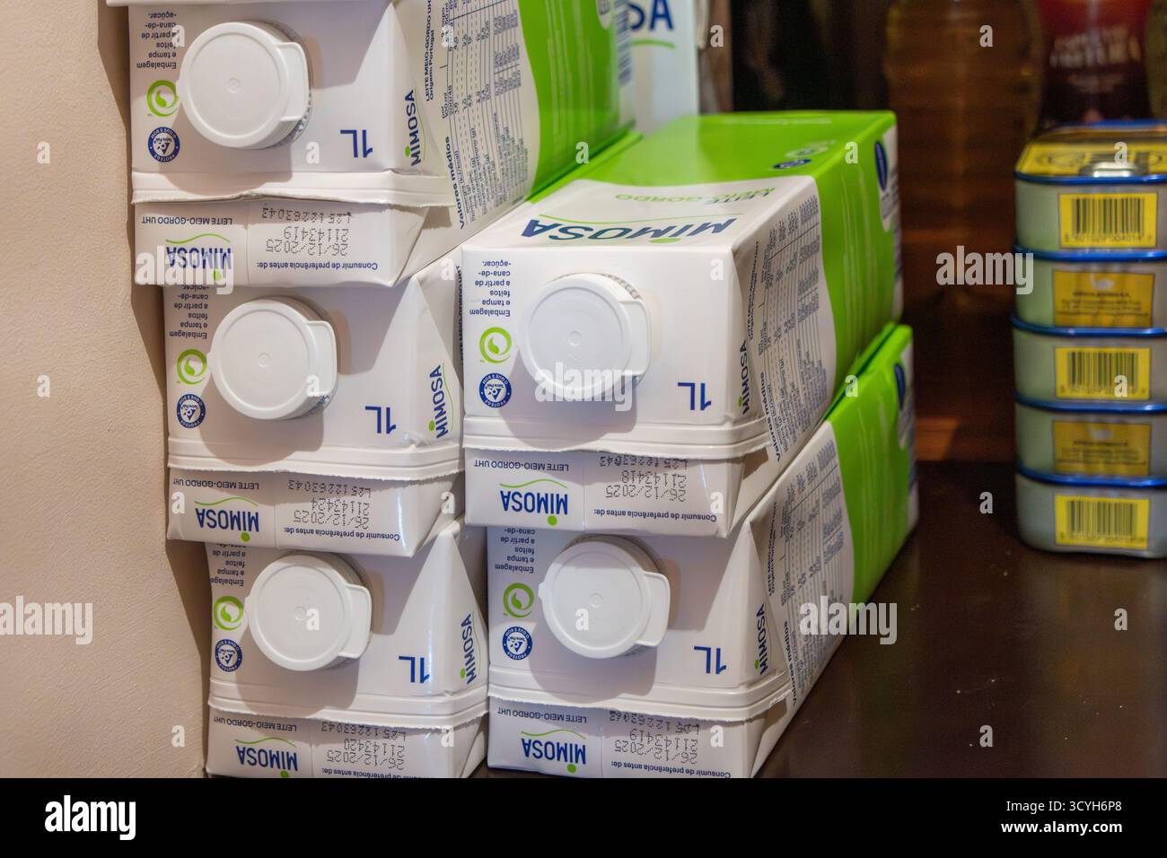 Diversi cartoni di latte mimosa sono impilati in una dispensa con altri alimenti Foto Stock