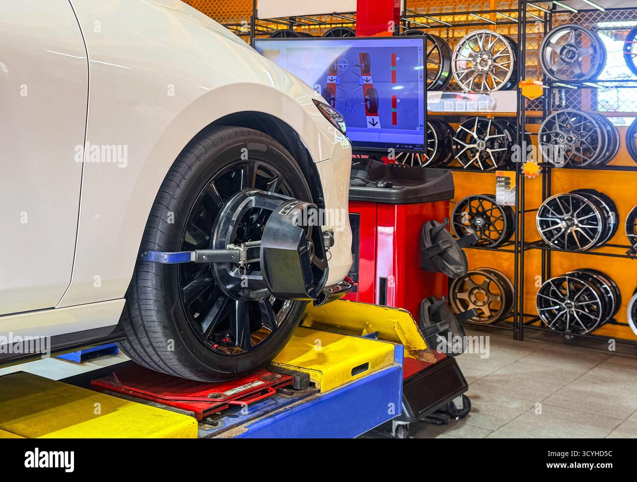 L'allineamento delle ruote del veicolo sul cavalletto con i sensori controlla nella stazione di servizio. Veicolo all'interno dell'officina per lavori di fissaggio della campanatura automatica, veicolo all'interno del garage Foto Stock