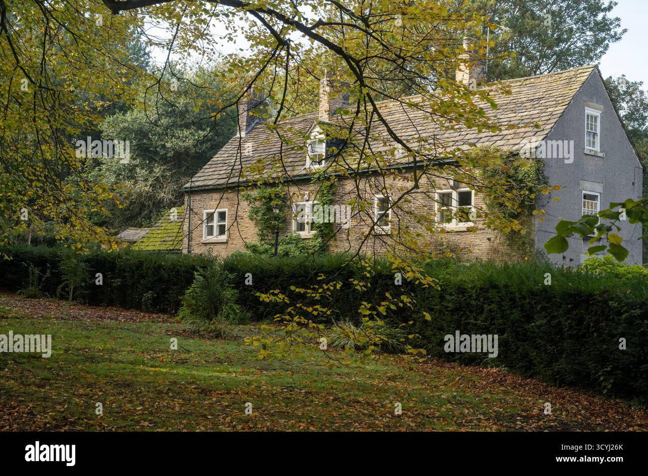Tradizionale cottage in pietra circondato da alberi autunnali a Wentworth, South Yorkshire, Inghilterra. Foto Stock