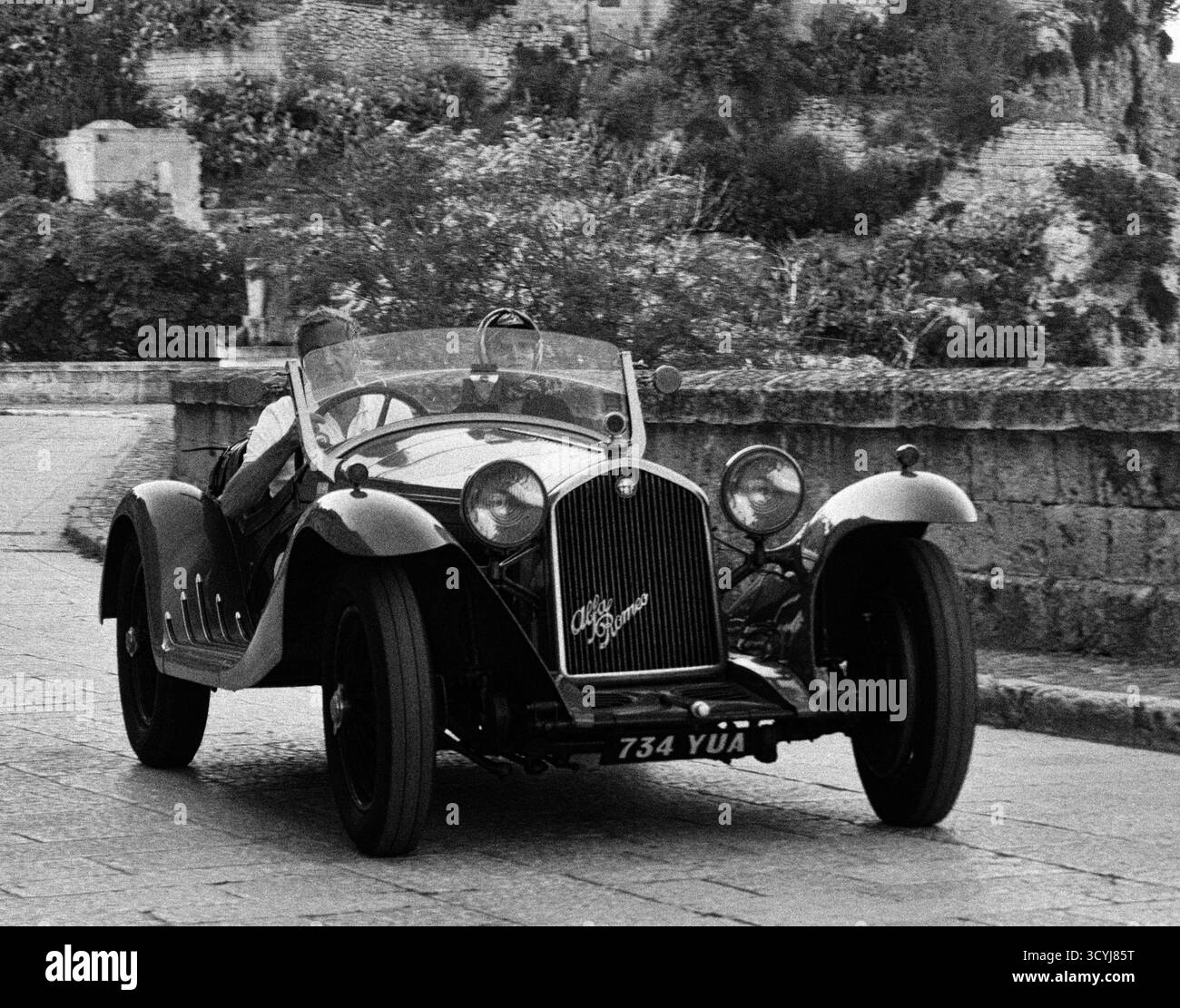 Auto sportiva d'epoca guidata in bianco e nero per le strade del villaggio italiano Foto Stock