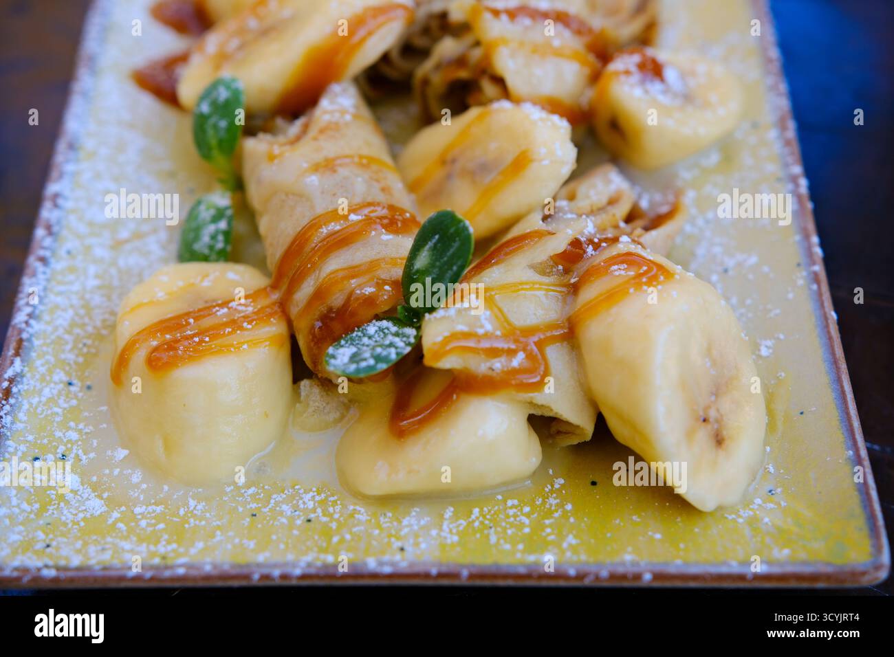 Crepes ripiene con spalmazione al cioccolato e banana su piatto bianco. Pancake sottili, blini. Dolce dolce. Foto di alta qualità Foto Stock