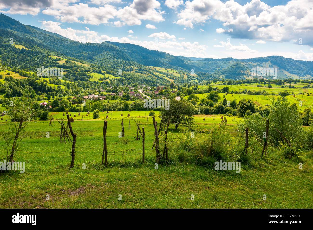 campi rurali sulle colline ondulate dell'ucraina in estate. ampio paesaggio di campagna di transcarpathia con recinzioni a bastone in luce soffusa. villa uzhok Foto Stock