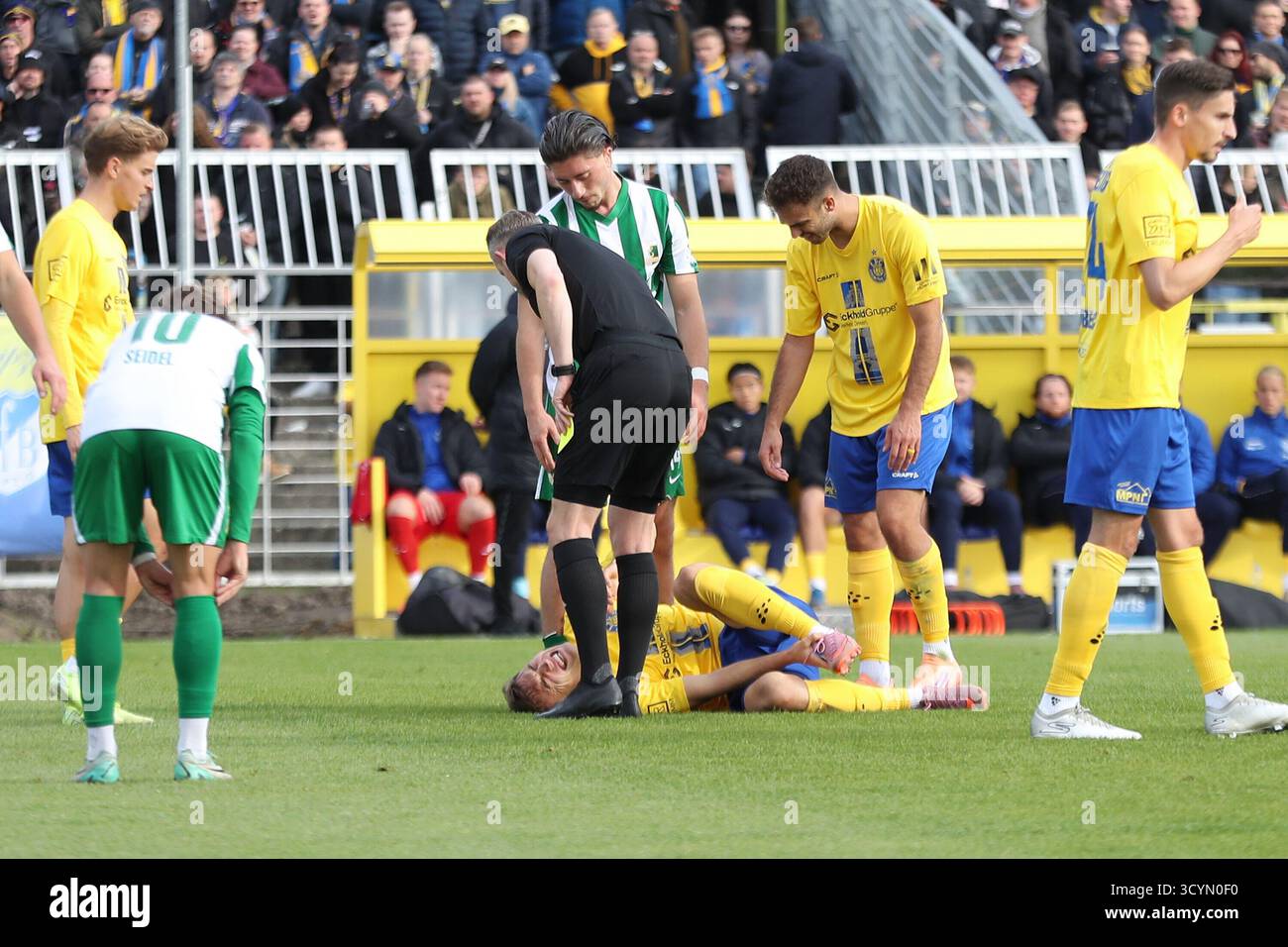 Lipsia, Germania. 19 ottobre 2025. Jonas Arcalean (17, Lok Leipzig) liegt nach einem foul mit Schmerzen am Boden. Schiedsrichter Florian Markhoff, Valon Aliji (14, Chemie Leipzig) und Farid Abderrahmane (8, Lok Leipzig) stehen um ihn. Fu?ball, Regionalliga Nordost, Saison 2025/ 2026, 12. Spieltag: 1. FC Lok Leipzig vs. BSG Chemie Leipzig AM 19.10.2025 im Bruno-Plache-Stadion, Lipsia. Credito: dpa/Alamy Live News Foto Stock