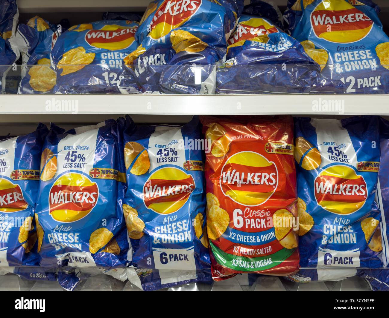 Più confezioni da 5 di patatine Walkers in diversi gusti sono impilate ordinatamente su uno scaffale del supermercato per la vendita nel Regno Unito. Foto Stock