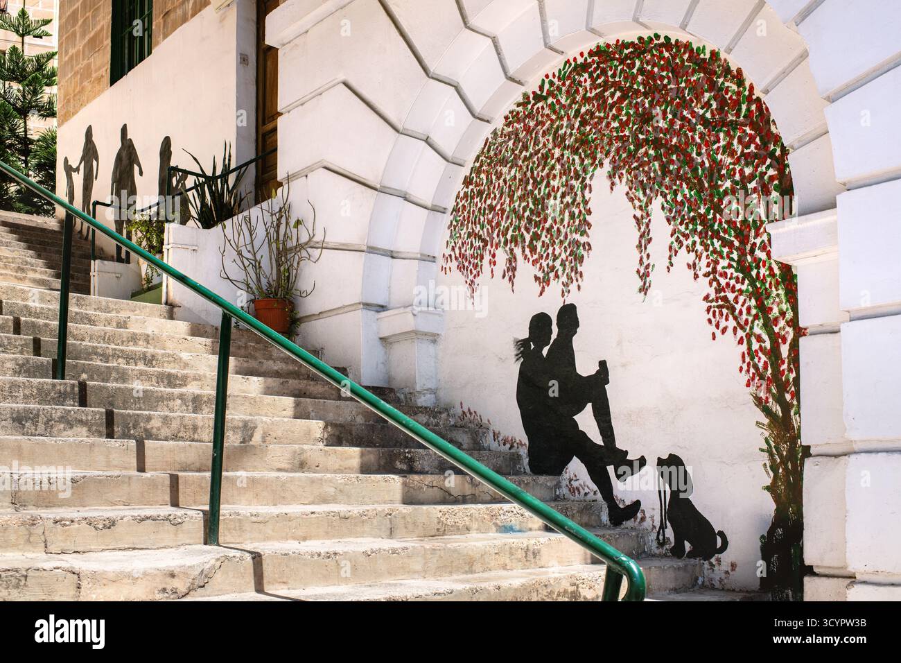 Bormla, Malta – 07.13.2025: Un murale accanto alla scalinata di una strada della città: Sagome nere di persone e un cane seduti sui gradini sottostanti. Foto Stock