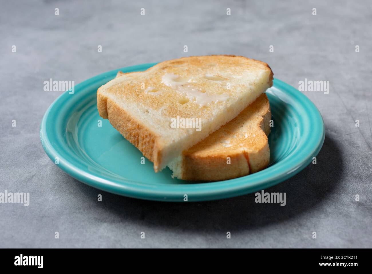 Vista di un piattino di pane bianco con spalmazione di burro. Foto Stock