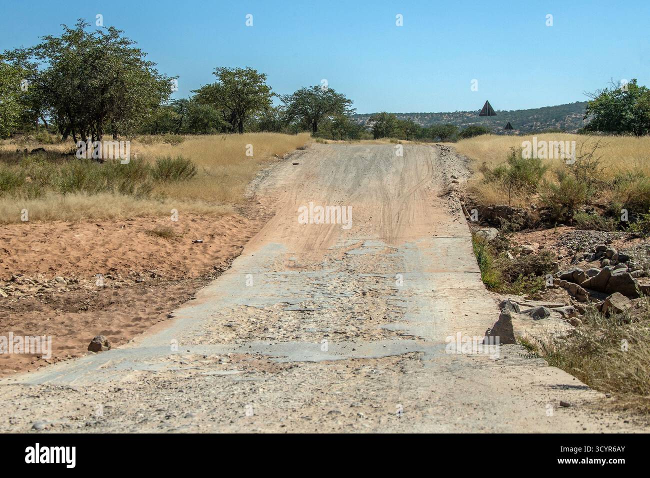 Un attraversamento pericoloso e gravemente danneggiato di un fiume asciutto; effimero, disseminato di rocce e cemento rotto; nel bosco di mopani, sulla strada C43 tra Foto Stock