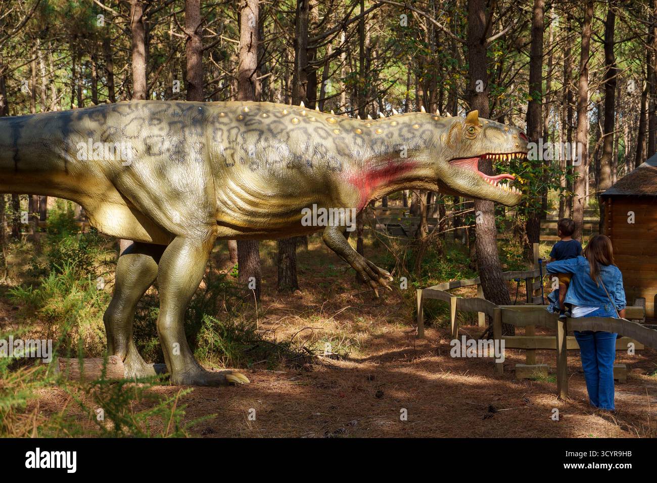 Una donna e un bambino osservano una grande scultura di dinosauri nel parco a tema dei dinosauri Dino Parque a Lourinhã, Portogallo, Europa Foto Stock
