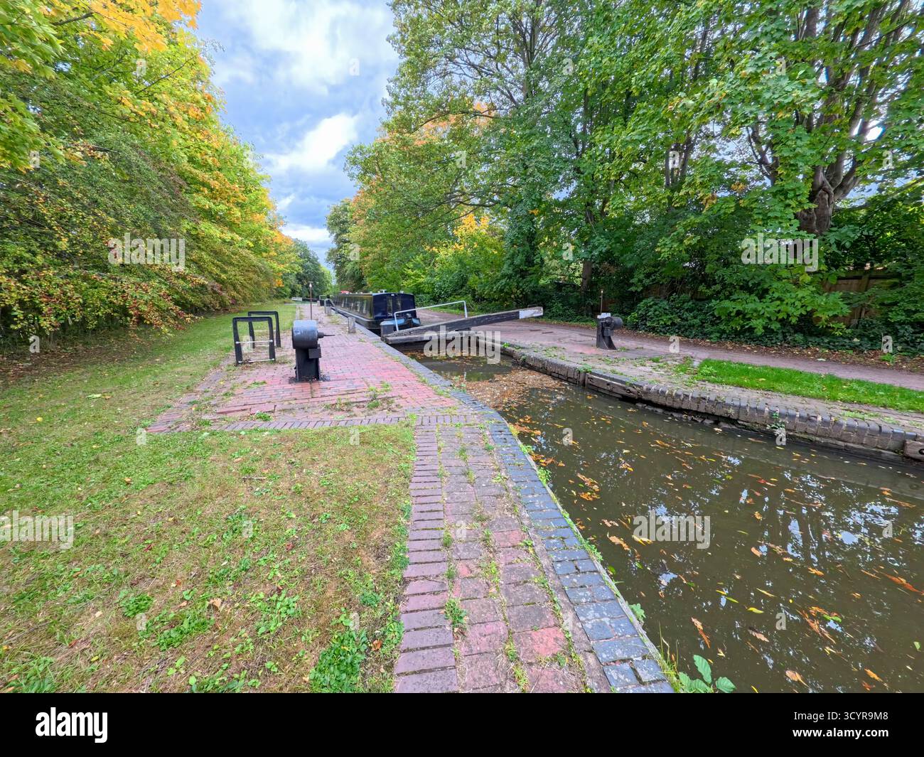 Viaggio in motoscafo attraverso la chiusa nel paesaggio rurale inglese sul canale del canale navigabile britannico con cielo blu nella stagione autunnale Foto Stock
