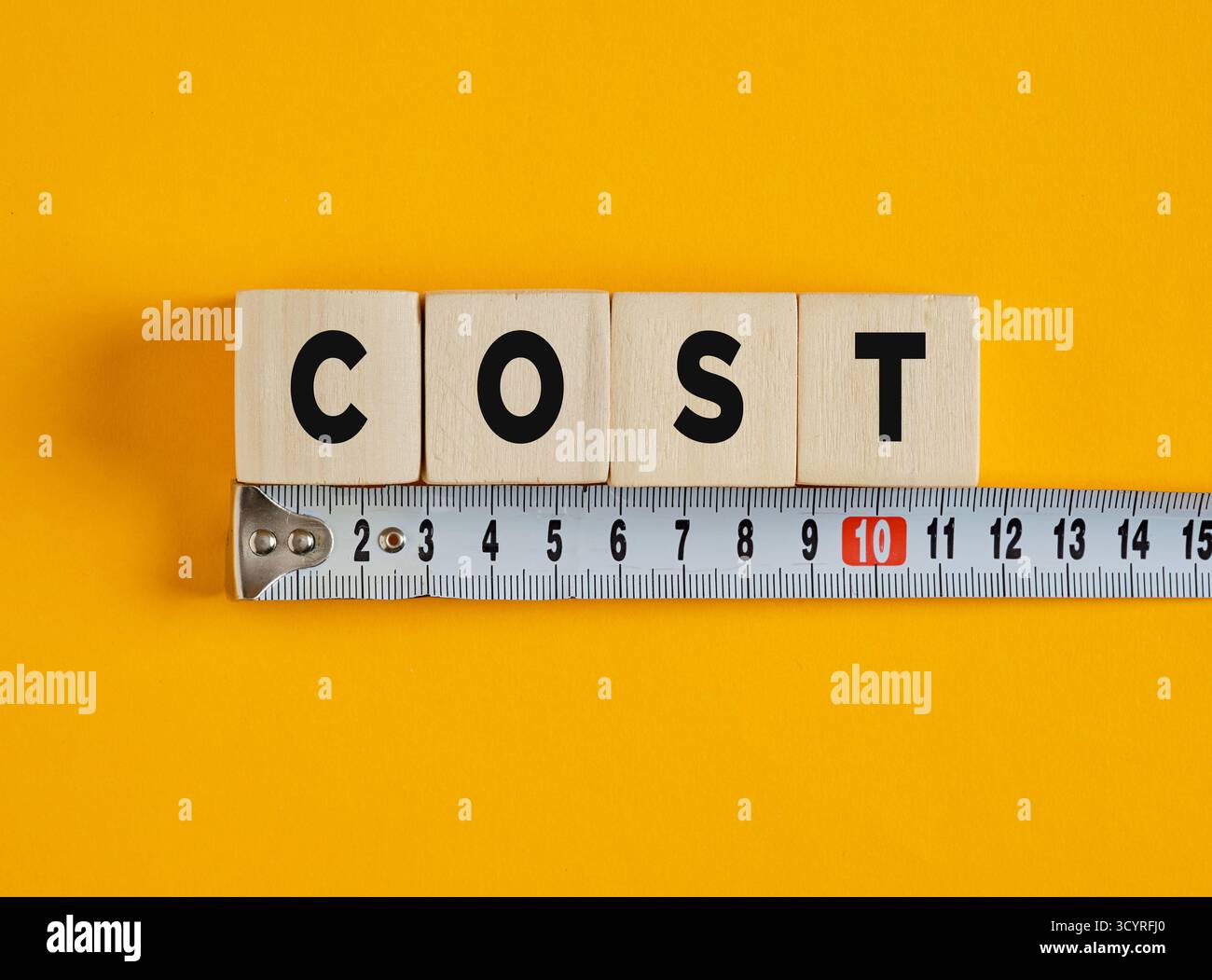 Cubi di legno che incidono i costi con un metro a nastro, simboleggiando il controllo dei costi e la gestione del budget Foto Stock