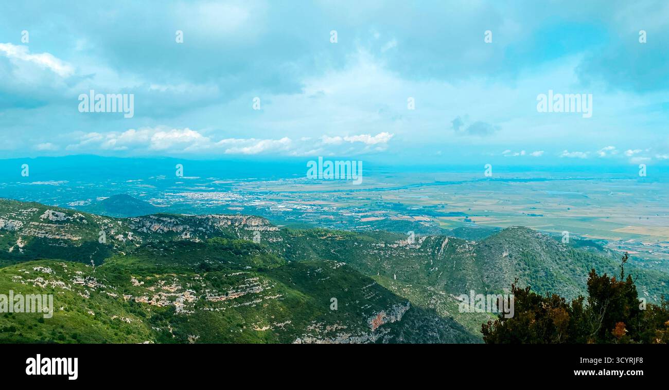 Vista aerea sui verdi pendii della Serra del Montsia nella Catalogna meridionale, in Spagna, con il fiume Ebro e i terreni agricoli del Delta dell'Ebro che si estendono per Foto Stock