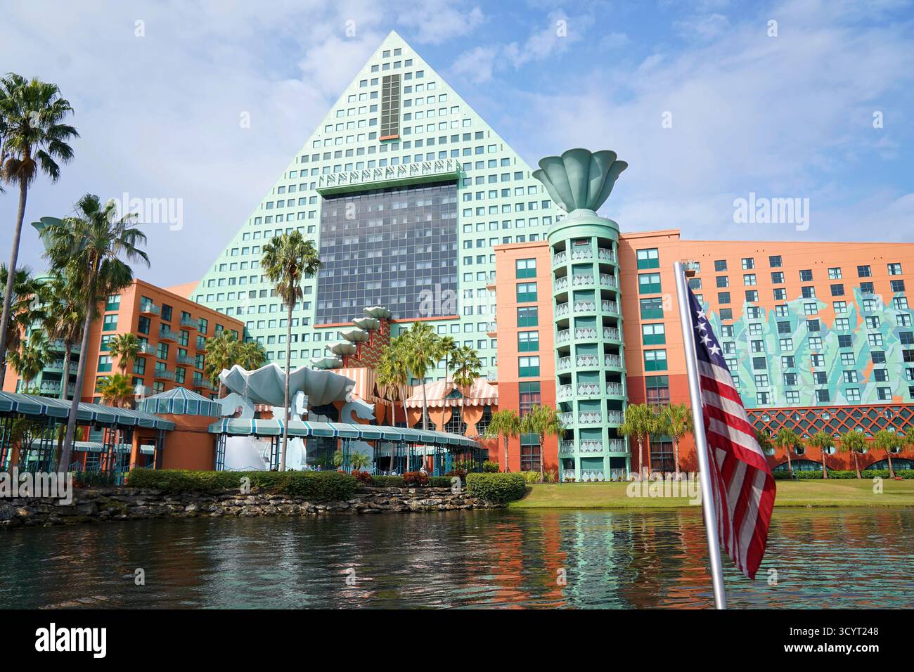Vista del Walt Disney World Dolphin Hotel dall'acqua, che mostra la sua struttura a piramide color acqua e la bandiera degli Stati Uniti in primo piano Foto Stock