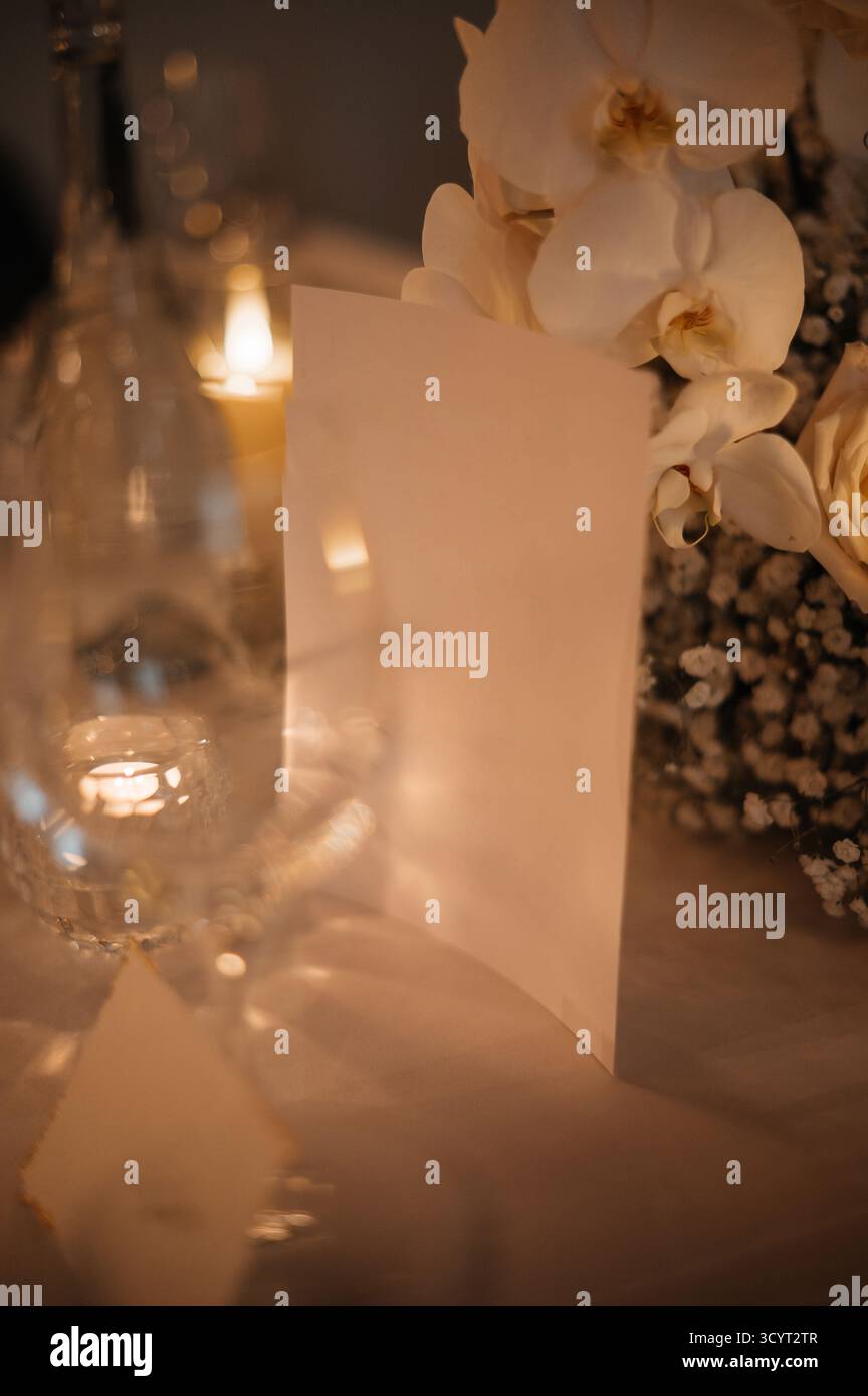 Elegante tavolo da pranzo con menu', candele e fiori. Foto Stock