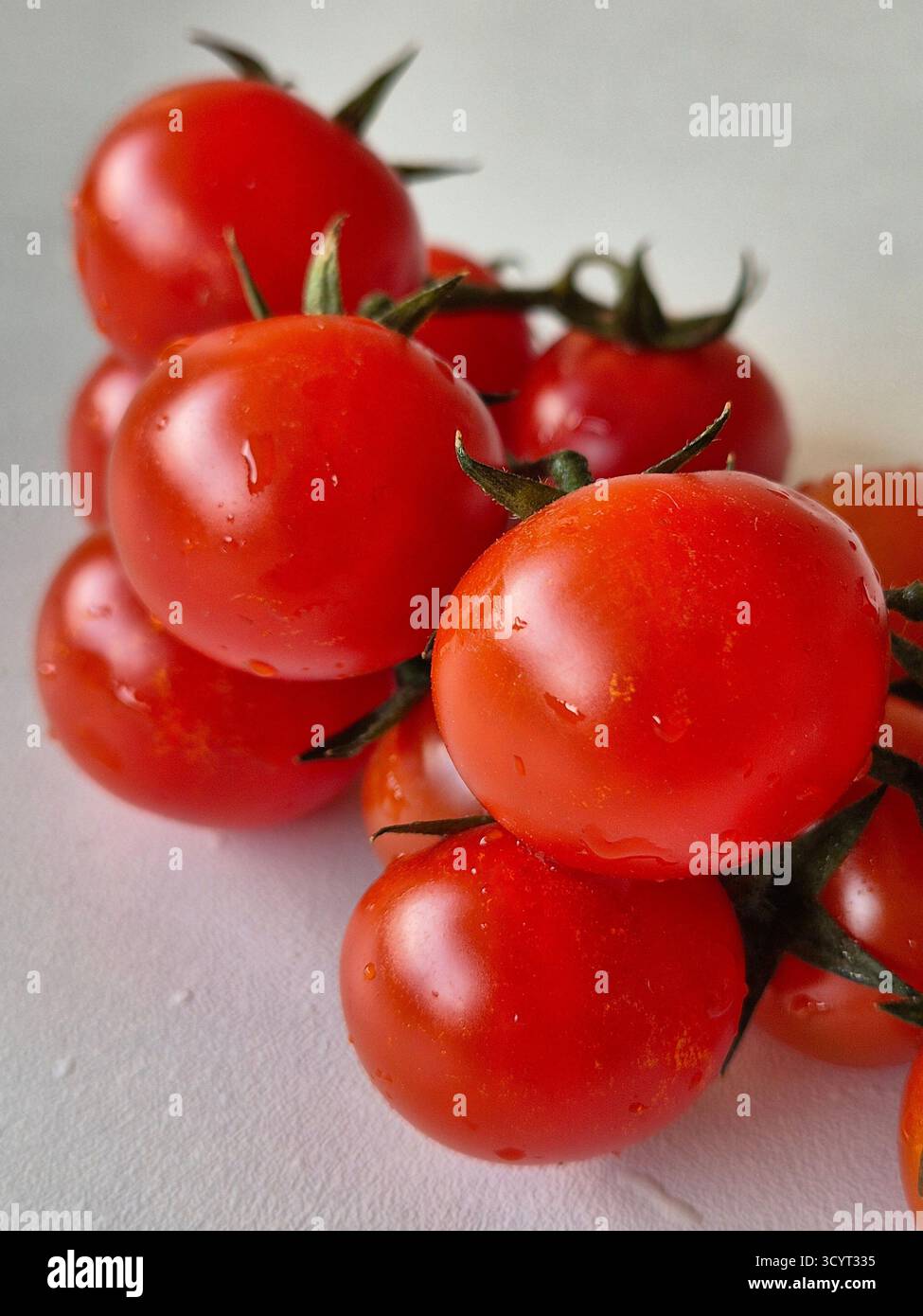 Pomodori ciliegini rossi su sfondo bianco. Primi piani di pomodori ciliegini rossi - Immagine stock catturata con smartphone