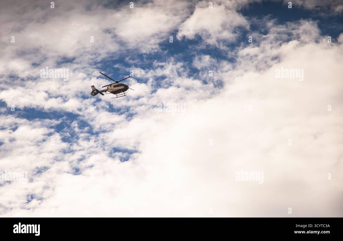 Elicottero della polizia che vola in cielo tra le nuvole Foto Stock