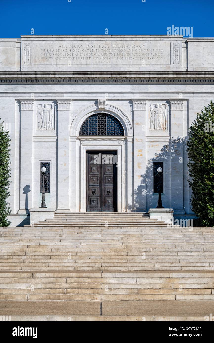 American Institute of Pharmacy Building Washington DC // WASHINGTON DC — l'American Institute of Pharmacy Building, sede nazionale dell'American Pharmacists Association (APHA), presenta la sua facciata in marmo neoclassico. Progettata dall'architetto John Russell Pope, questa grande struttura fu completata nel 1933 e formalmente dedicata nel 1934. L'iscrizione prominente dell'edificio onora i contribuenti alla salute pubblica e alla scienza della farmacia, notando l'anno MCMXXI (1921). Sculture in rilievo raffiguranti figure e dettagli ornati adornano l'ingresso. Situato al 2215 di Constitution Avenue NW, è un cartello Foto Stock