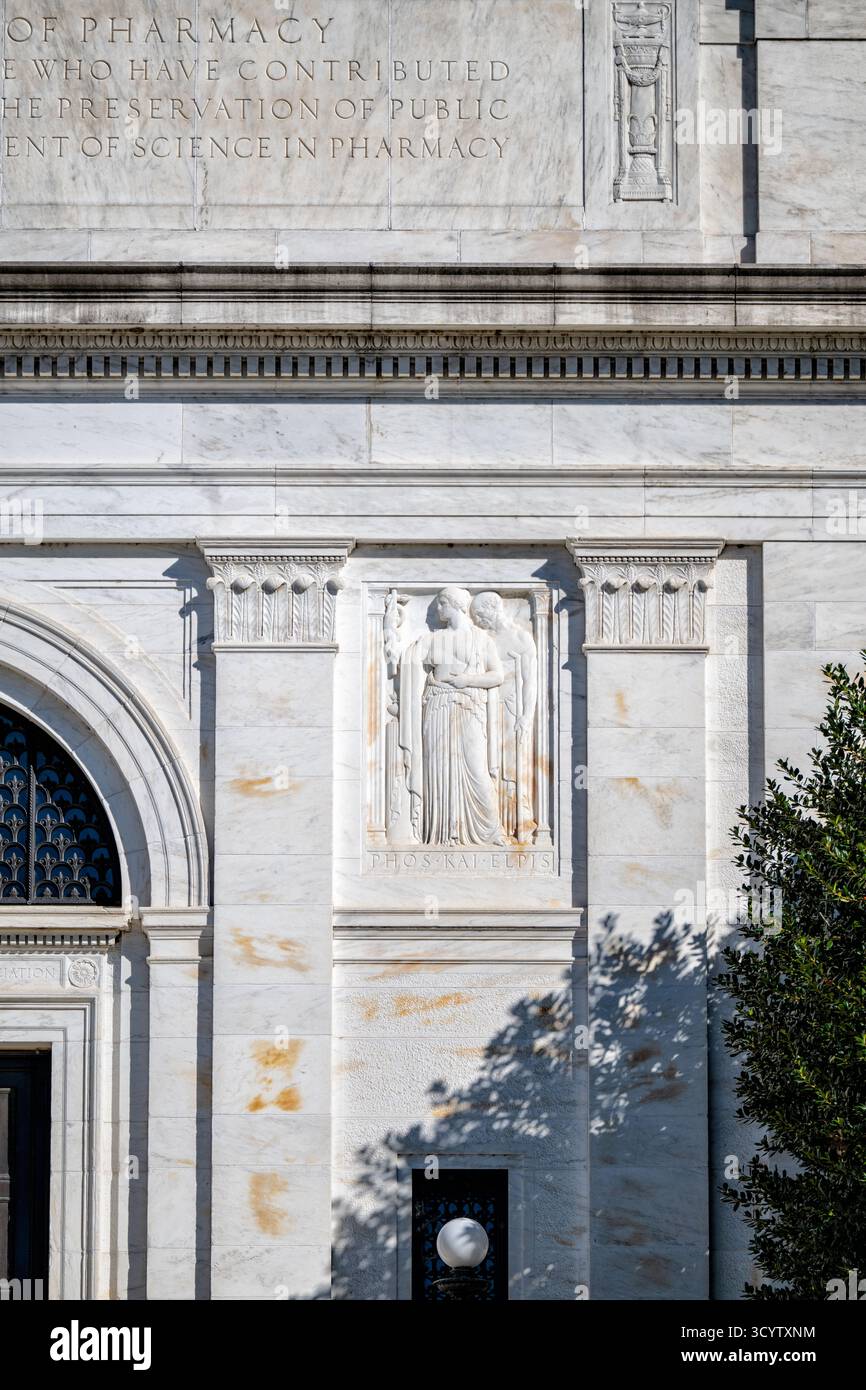 American Institute Of Pharmacy Building Bas Relief Washington DC | WASHINGTON D.C., Stati Uniti — Un bassorilievo in marmo con l'iscrizione "Phos Kai Elpis" (Luce e Speranza) decora la facciata dell'American Pharmacists Association Building al 2215 Constitution Avenue NW. Intagliato da Ulysses A. Ricci nel 1933 per il progetto neoclassico di John Russell Pope, il pannello raffigura una figura che porta il bastone di Asclepio e guida un uomo malato verso la luce della conoscenza. Foto Stock