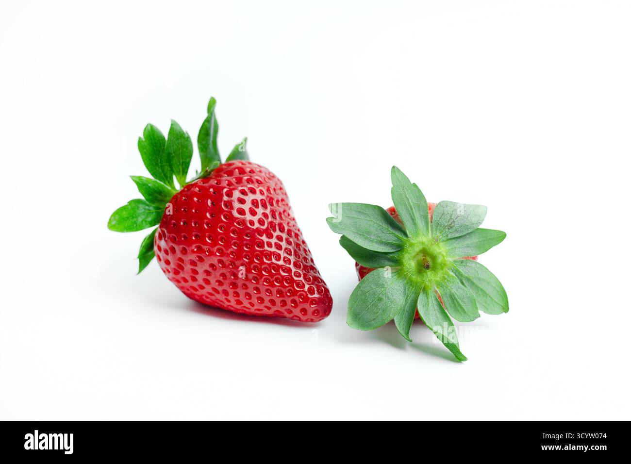 Due fragole fresche, una verticale e una con foglie verdi, su sfondo bianco. Ideale per cibi sani e grafica di branding organica. Foto Stock