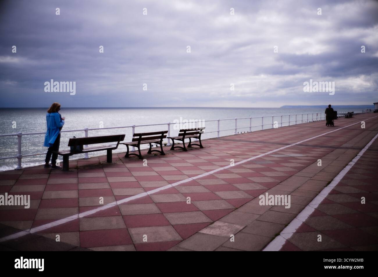 La delicata attenzione di una donna solitaria che invia SMS su un telefono cellulare sul lungomare di Hastings Foto Stock