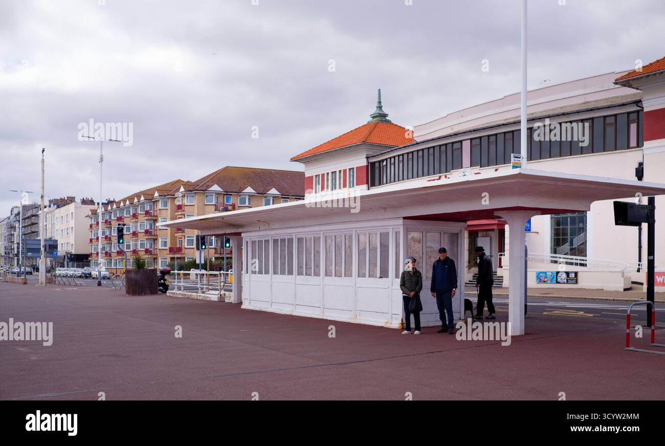 Persone che aspettano presso una fermata dell'autobus sul mare a Hastings vicino al molo Foto Stock