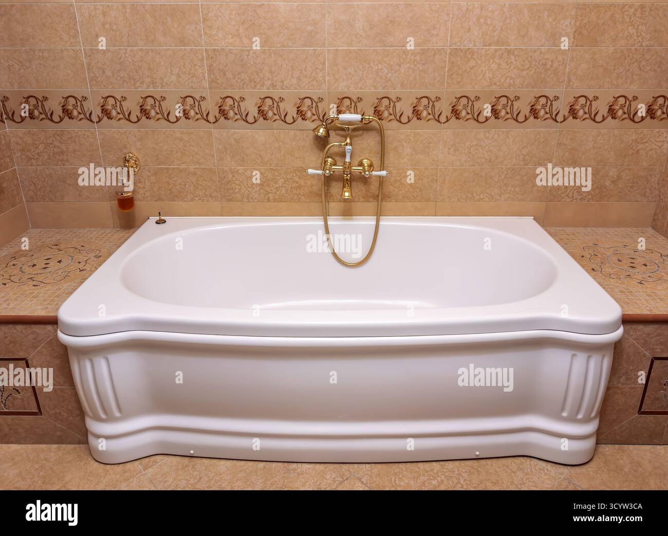 Vasca da bagno opulenta e invitante in un bagno splendidamente piastrellato, che mette in risalto rubinetti dorati d'ispirazione vintage e una spaziosa vasca perfetta per un Foto Stock