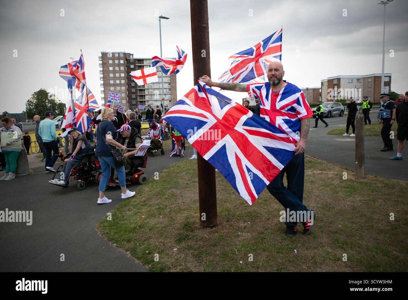 Un uomo con una bandiera Union Jack a una demonizzazione anti-migrante fuori dal vicino Britannia Hotel nel sobborgo di Seacroft a Leeds, West York Foto Stock