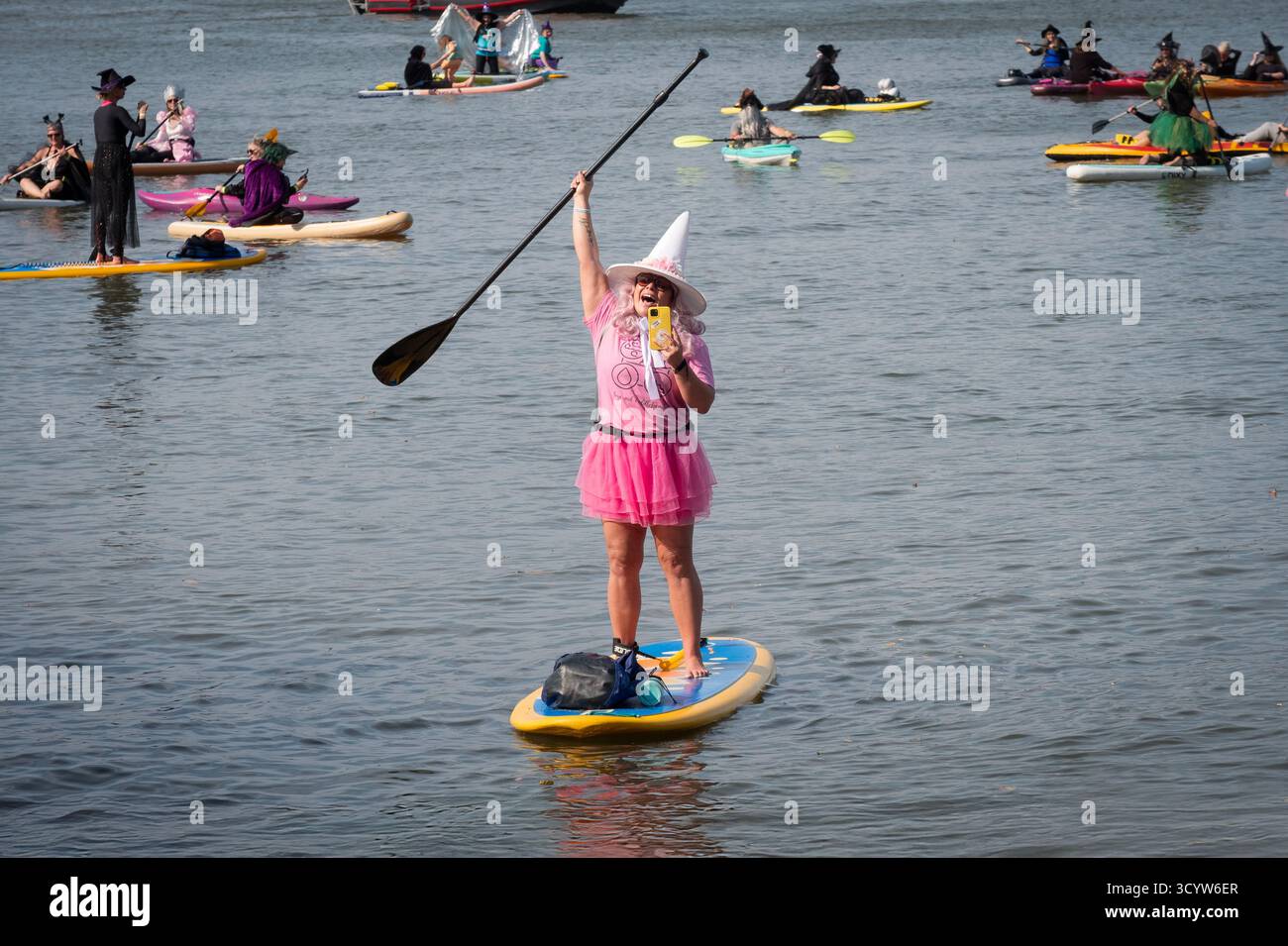 Una strega vestita di rosa si fa un selfie al SUP Witches of Sleepy Hollow Festival del 2025 pagaia sul fiume Hudson. Foto Stock
