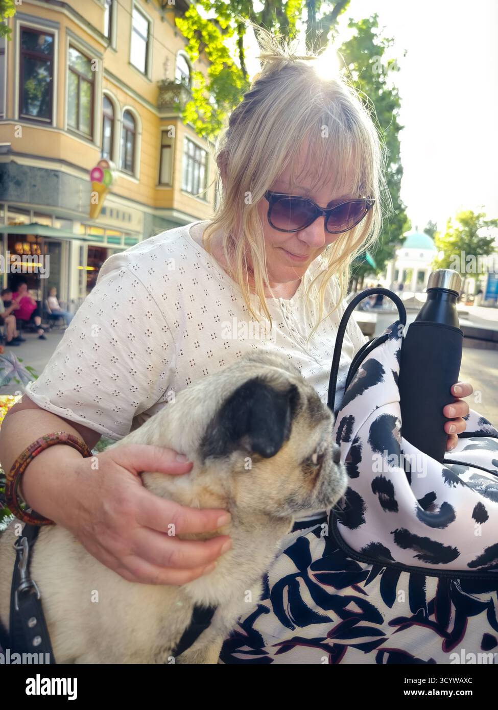 Donna di 50 anni seduta su una panchina con un cucciolo a Bad Pyrmont, Germania. Davvero foto da smartphone. Foto Stock