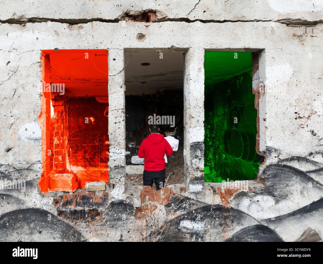 Un uomo in mezzo all'edificio distrutto dalla guerra. Sono mostrati i colori della bandiera palestinese. Foto Stock