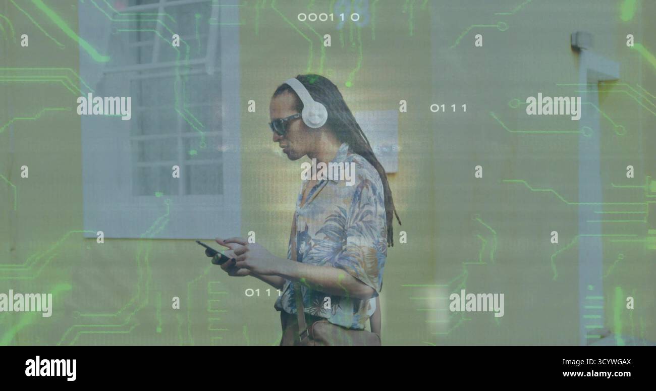 Uomo che cammina in strada, davanti al muro, indossa camicia floreale, cuffie, borsa da trasporto sotto i circuiti Foto Stock