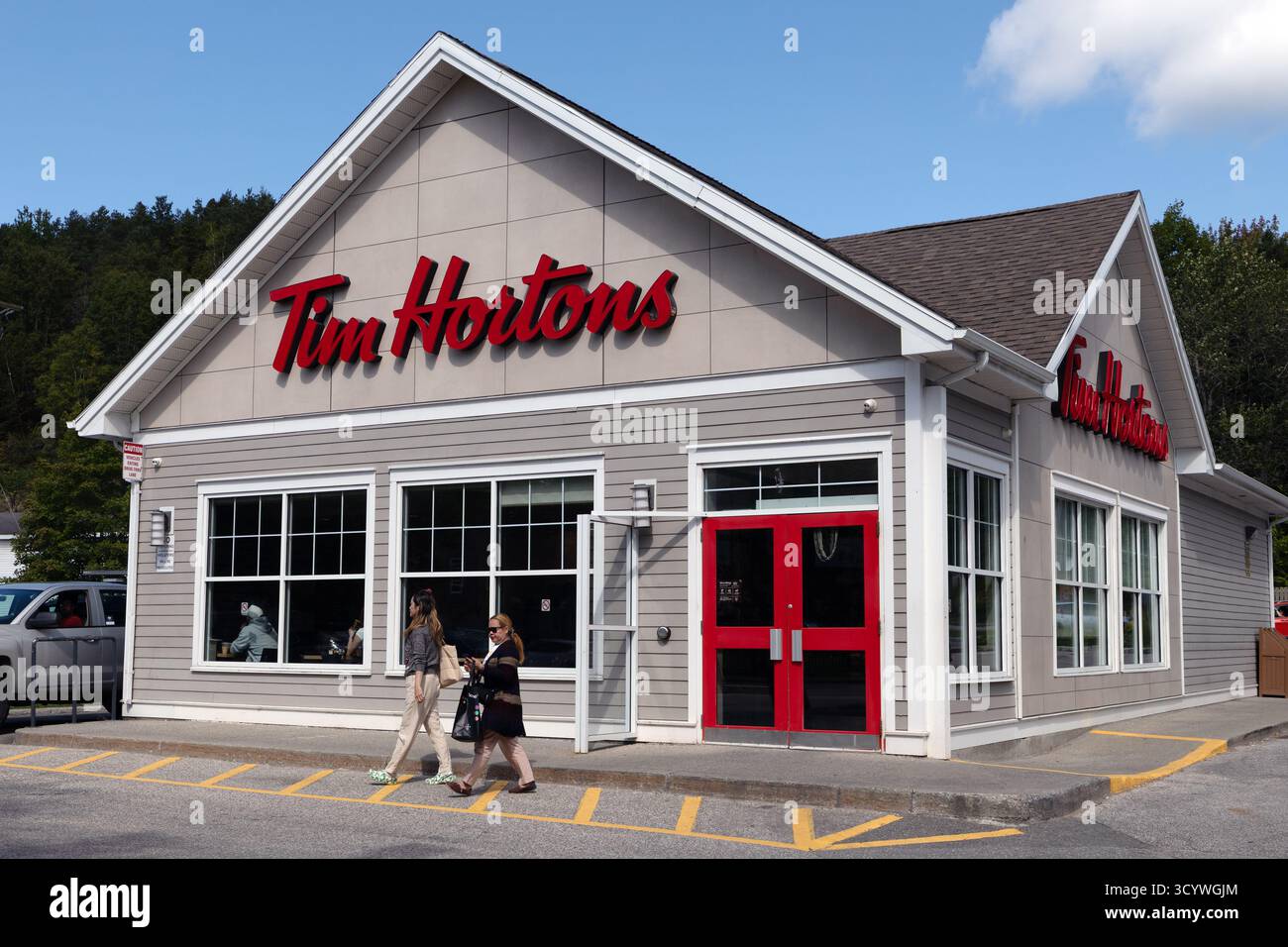 People Walking Tim Horton's Past Coffee Shop Building con Red incorniciata Door Foto Stock