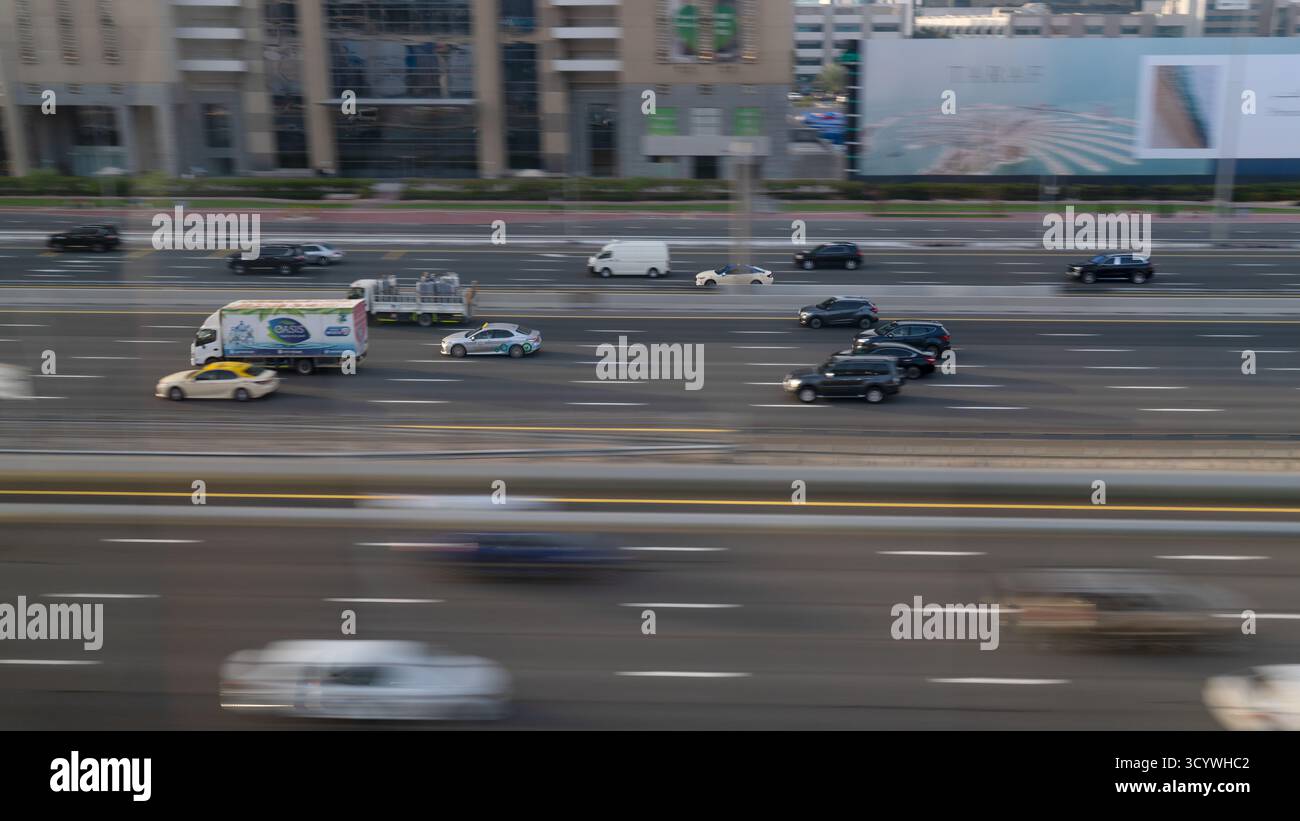 Dubai, Sheikh Zayed Rd, Emirati Arabi Uniti - 3 febbraio 2023: Una moltitudine di auto che si muovono rapidamente lungo un'ampia autostrada a più corsie. Gli edifici e i cartelloni lo sono Foto Stock