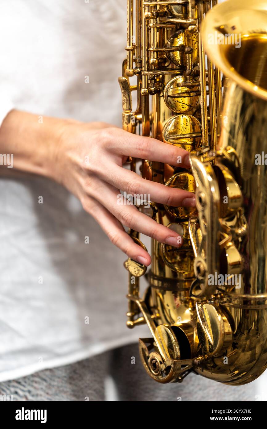 Musicista mano che suona un sassofono di ottone, premendo i tasti per creare musica Foto Stock
