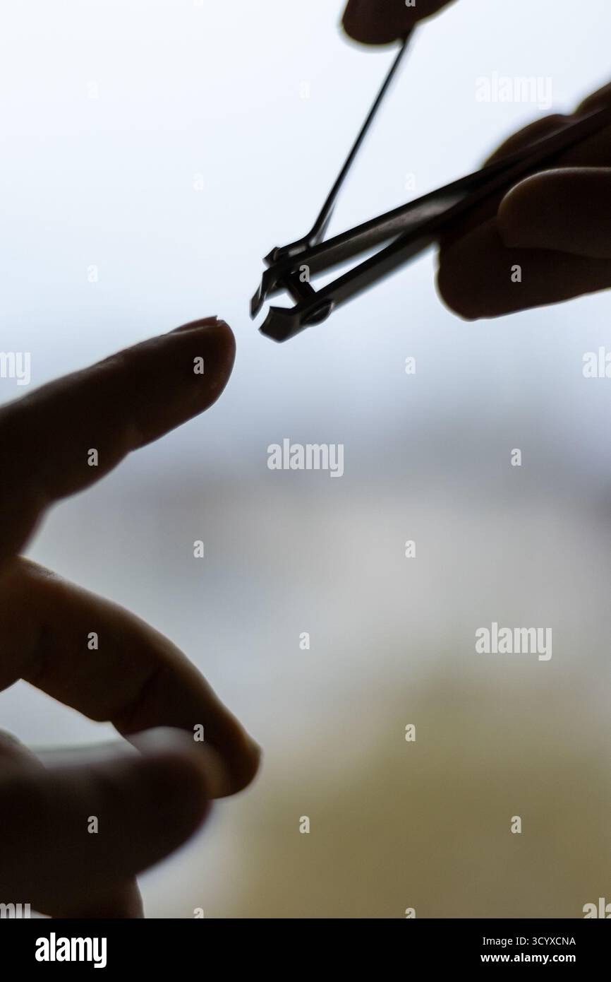 Uomo che taglia le unghie con le lame. Una visione dettagliata delle mani di un uomo che taglia le unghie in un momento di cura personale, evidenziando l'igiene. Foto Stock