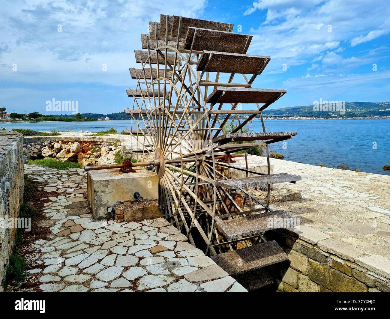 Uno storico mulino ad acqua sullo sfondo del mare e del cielo blu ad Argostoli, sull'isola di Cefalonia, in Grecia Foto Stock