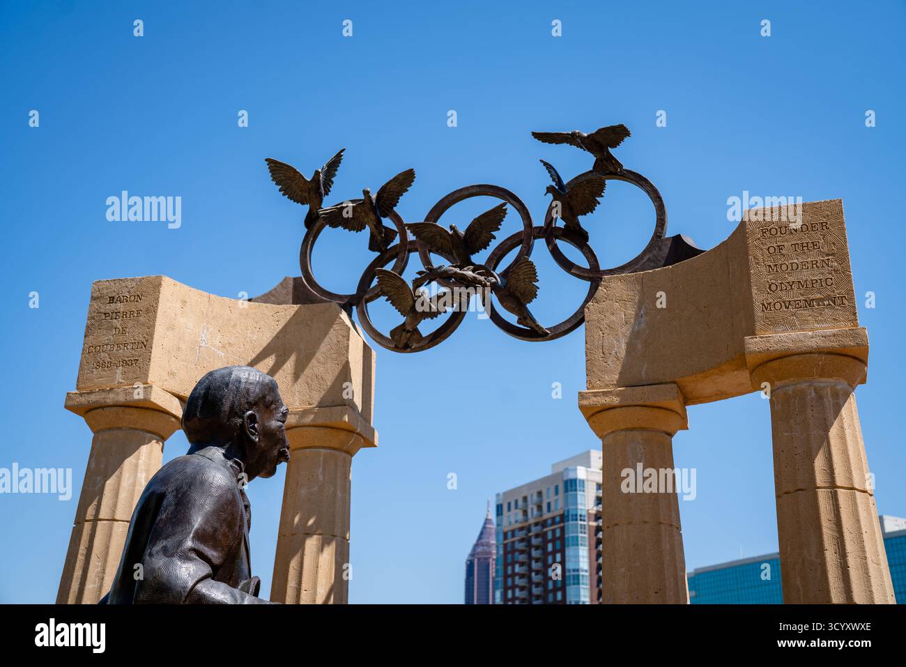 Primo piano della statua del barone Pierre de Coubertin al Centennial Olympic Park, con colombe di bronzo e anelli olimpici Foto Stock