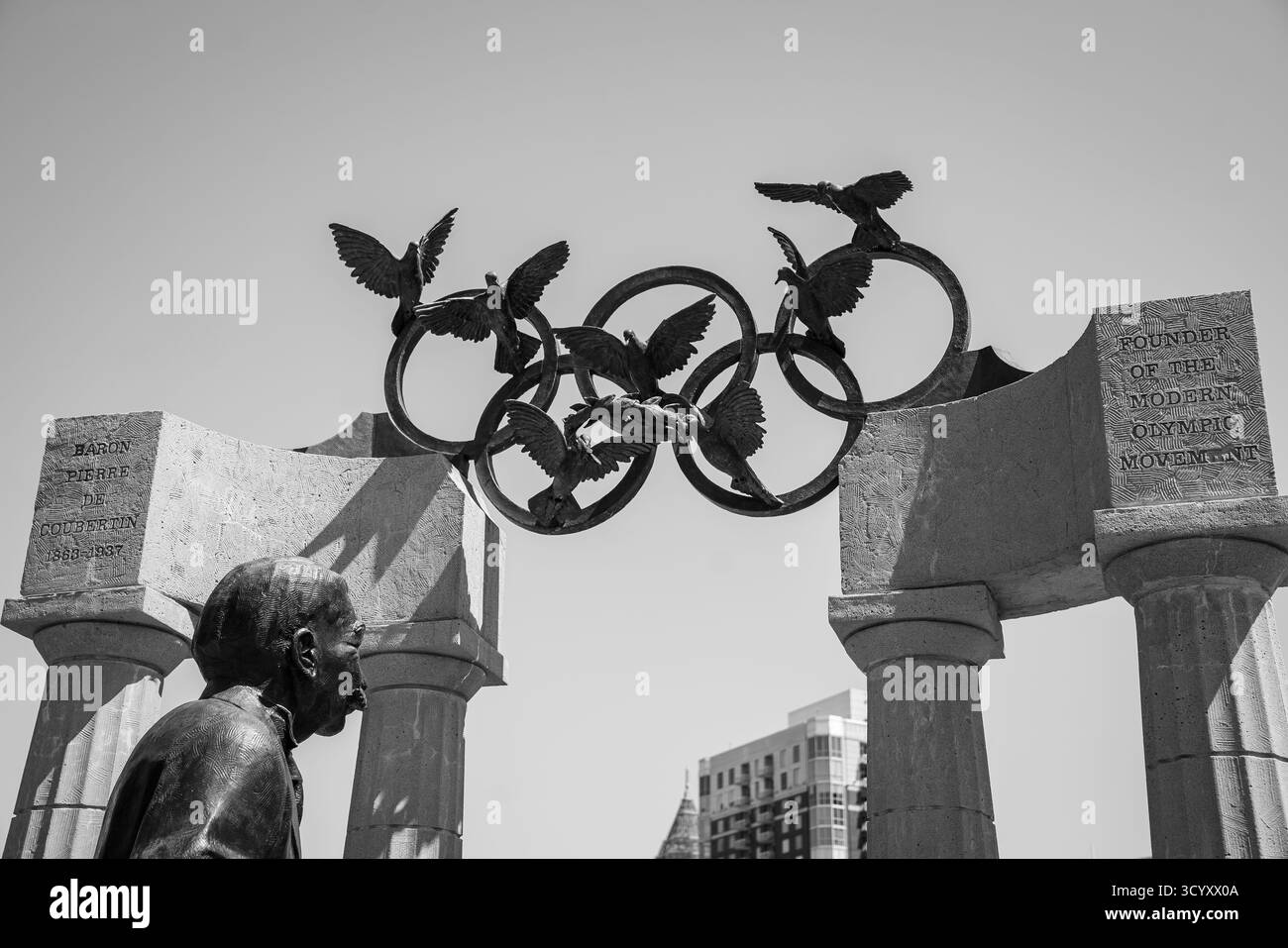 Primo piano della statua del barone Pierre de Coubertin al Centennial Olympic Park, con colombe di bronzo e anelli olimpici in bianco e nero Foto Stock