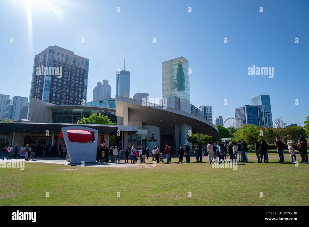 I visitatori si allineano fuori dal mondo della Coca-Cola a Pemberton Place in una mattinata di sole, con lo skyline di Atlanta sullo sfondo Foto Stock