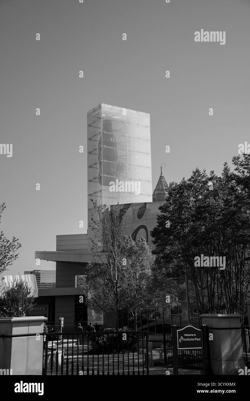 La torre di vetro della Coca-Cola sorge sopra il World of Coca-Cola a Pemberton Place, incorniciata da alberi e un cielo azzurro limpido in bianco e nero Foto Stock