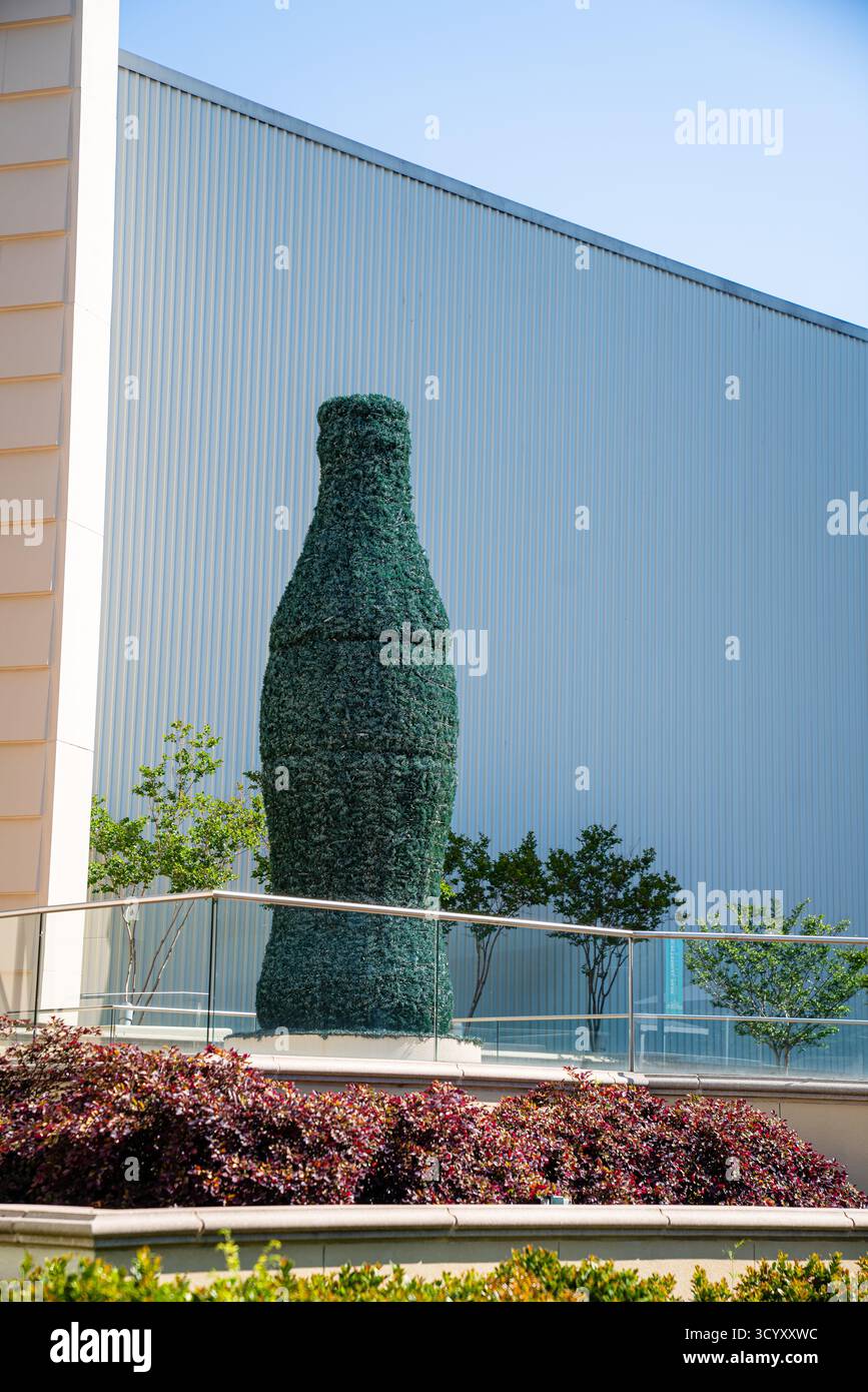 Un topiario a forma di iconica bottiglia di Coca-Cola si erge fuori dall'edificio World of Coca-Cola in Baker Street sotto un cielo azzurro Foto Stock