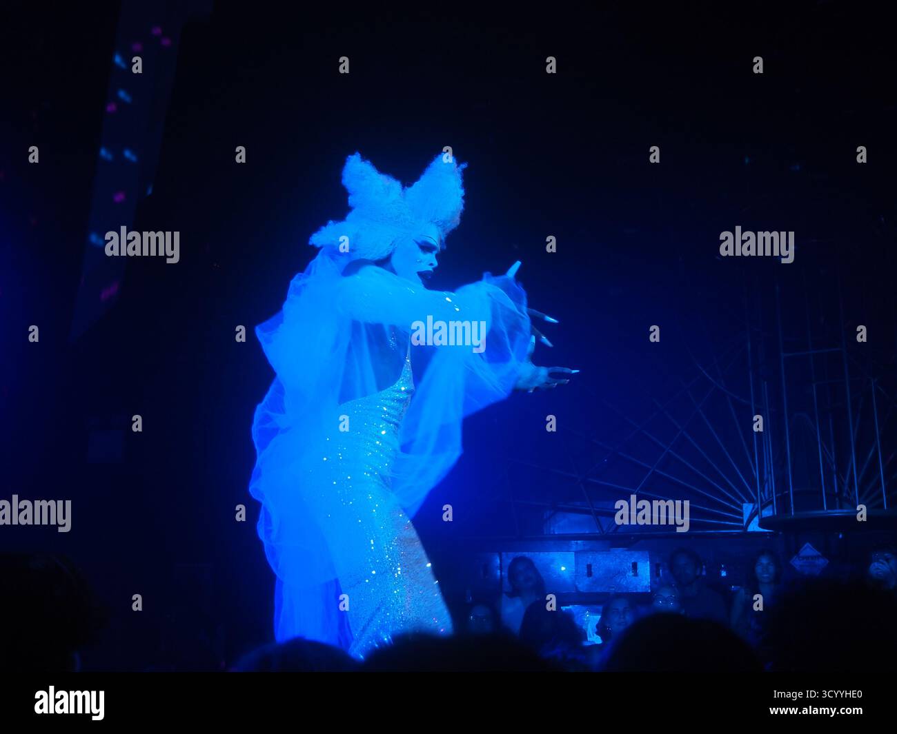 Trascina l'artista sul palco sotto la luce blu alla House of Yes di Williamsburg, Brooklyn, New York, con costumi d'avanguardia e movimenti espressivi Foto Stock