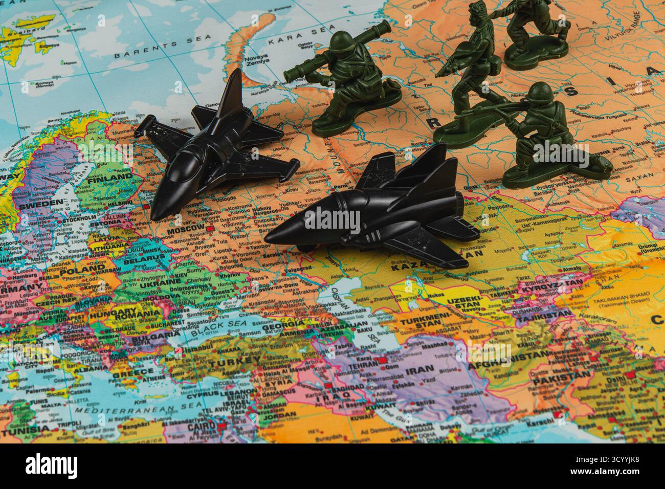 Due getti giocattolo neri e figure verdi dell'esercito si trovano su una mappa colorata del mondo, che indica le regioni di interesse militare. La mappa mostra vari paesi e ci Foto Stock Due getti giocattolo neri e figure verdi dell'esercito si trovano su una mappa colorata del mondo, che indica le regioni di interesse militare. La mappa mostra vari paesi e ci Foto Stock